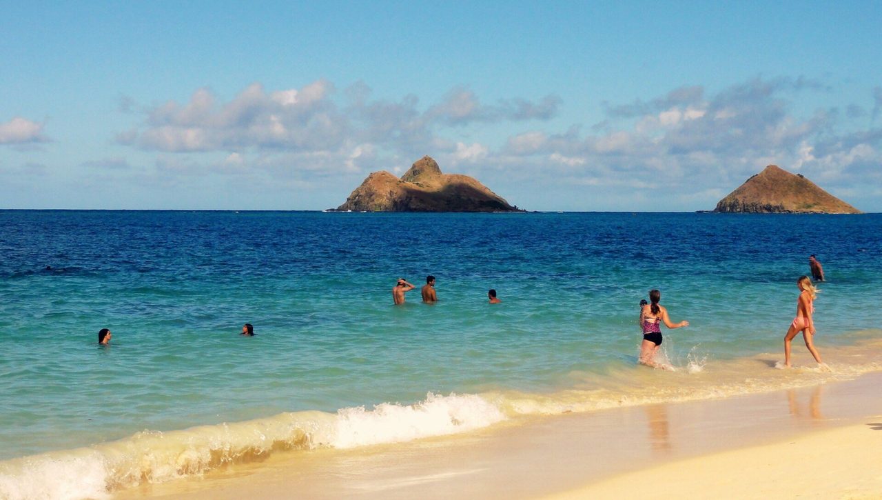 Swimmers in turquoise water off Lanikai with the two Mokulua islands behind
