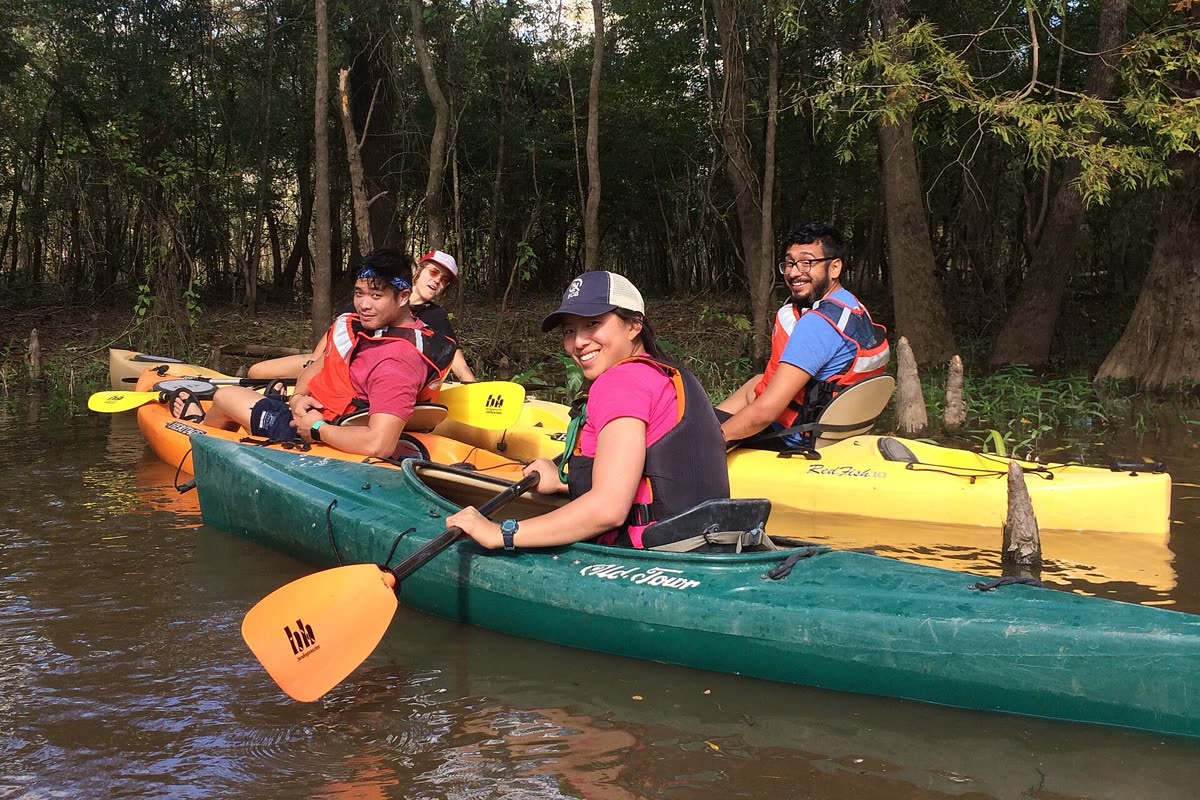 Friends laughing together while kayaking a forest waterway