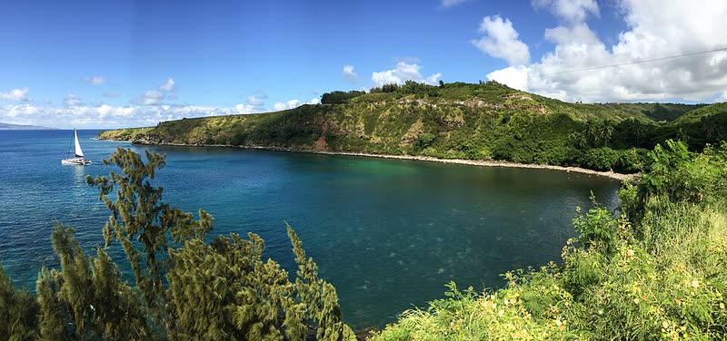 Deep blue Honolua Bay framed by green cliffs on Maui's northwest coast.