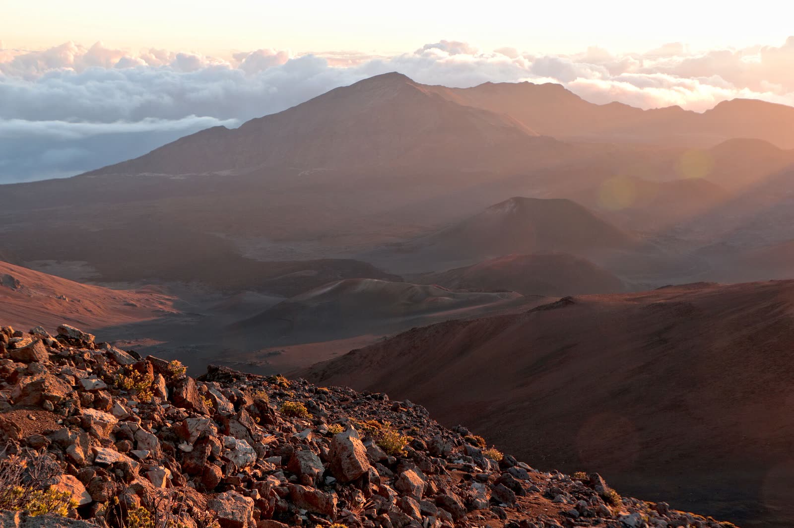 Early morning light spreads across the vast volcanic crater of Haleakalā on Maui.