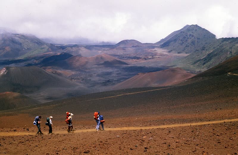 Hikers walk the Sliding Sands Trail down into Haleakalā's colorful volcanic crater.