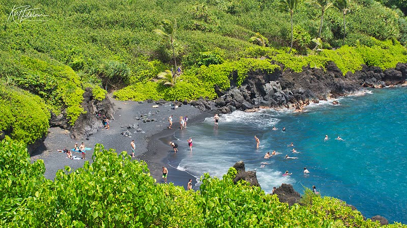 Swimmers enjoy turquoise water at the black sand Honokalani Beach in Waiʻānapanapa State Park.